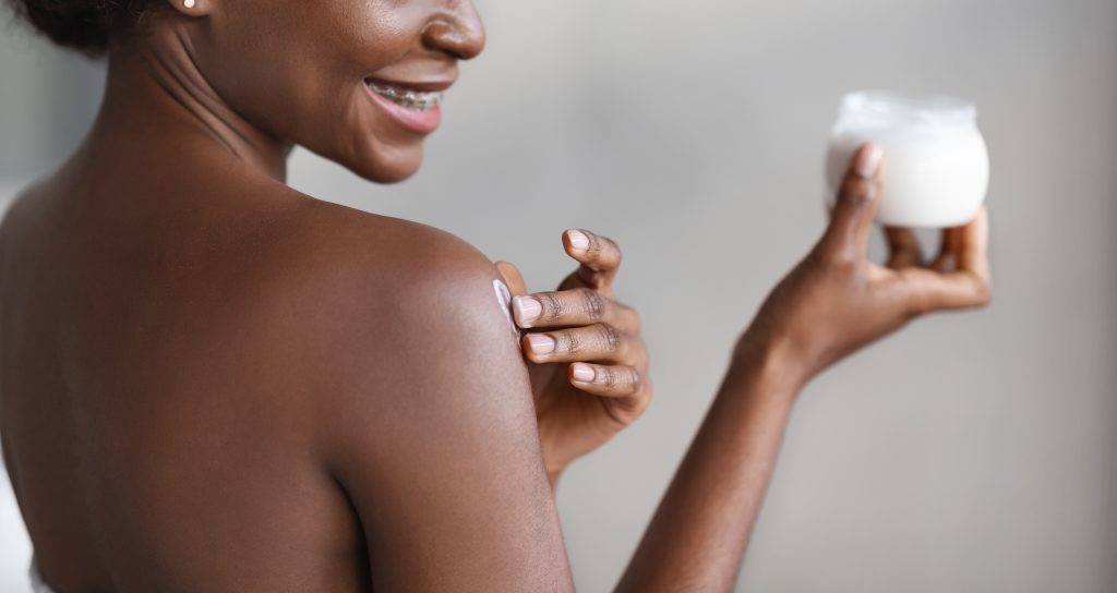 Unrecognizable african american woman applying skin butter on her shoulder